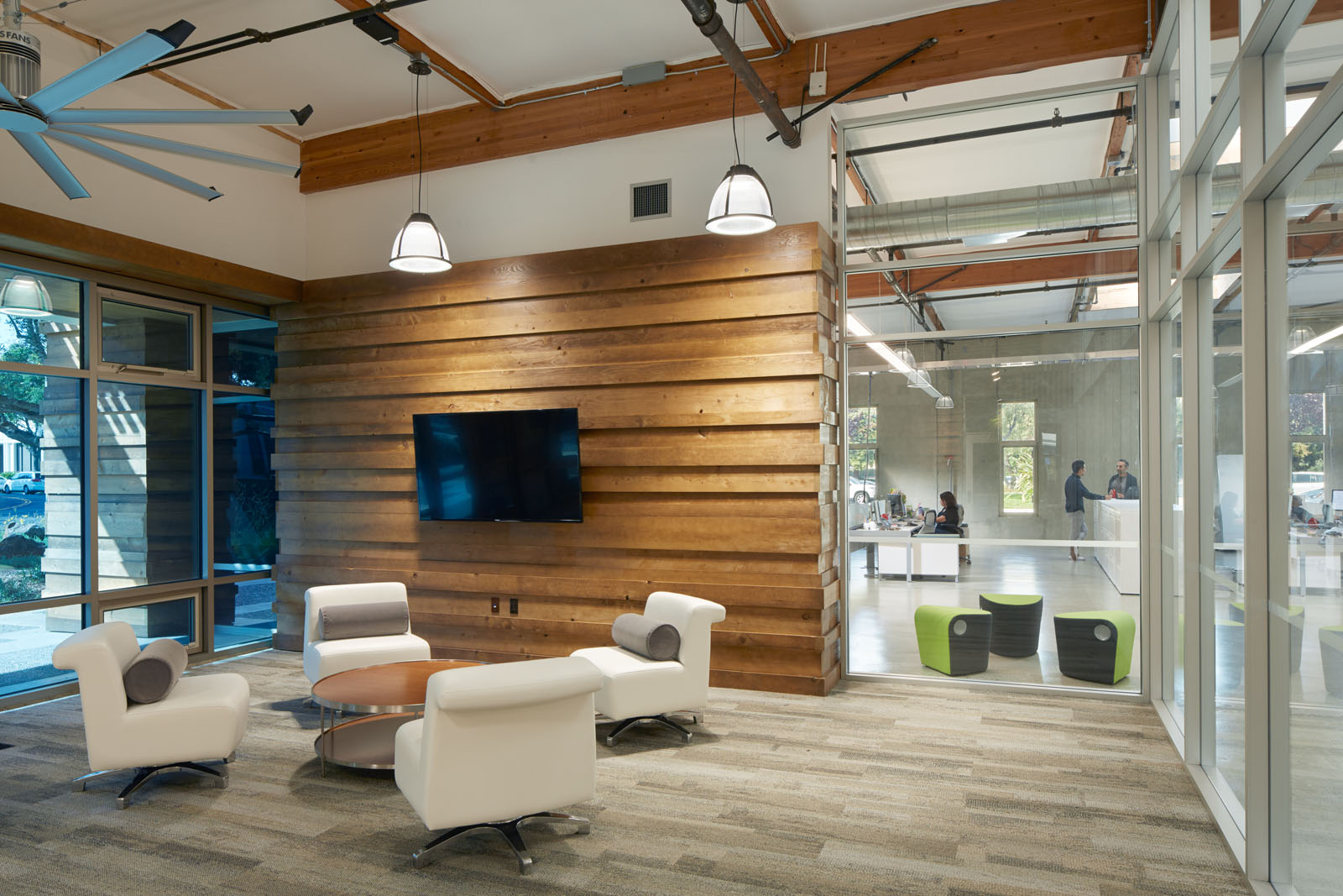 A lobby at 435 Indio. Reclaimed wood wall, fan overhead, glass to the open office.