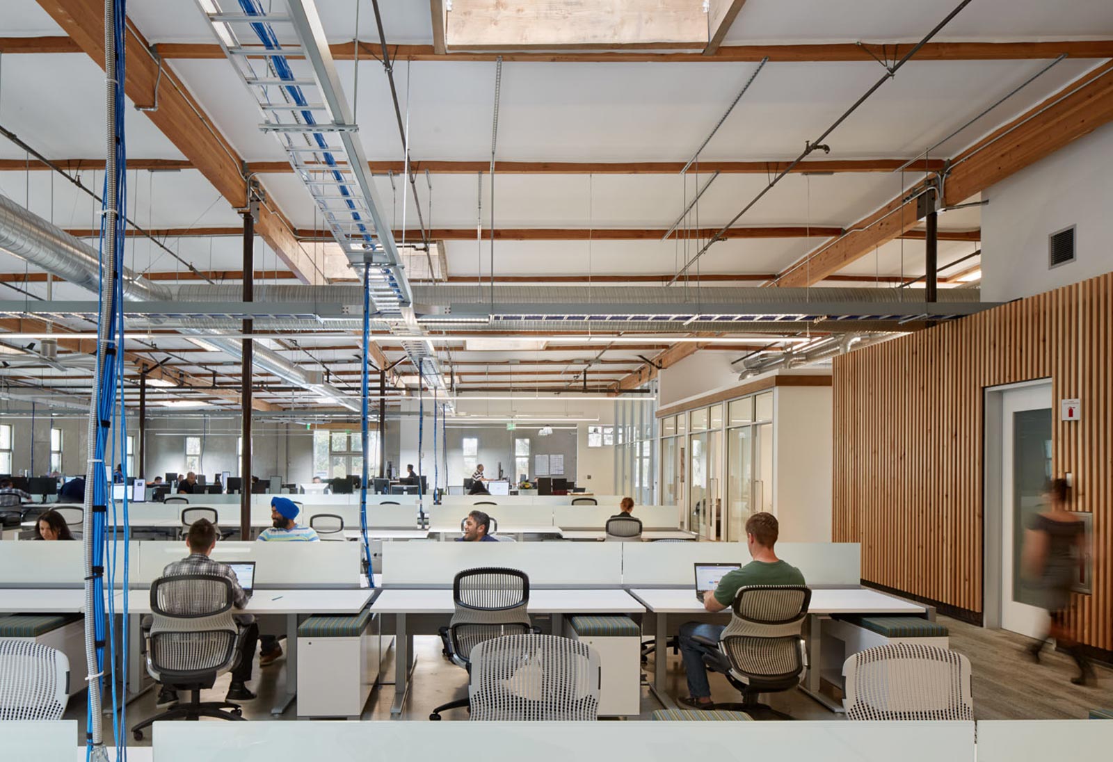 People working inside 435 Indio under skylights and a wood ceiling.